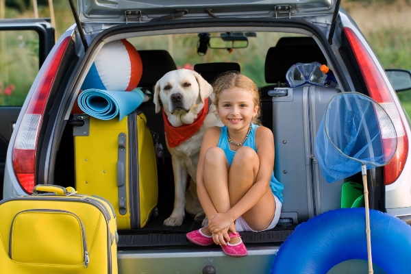 Maedchen fertig fuer Urlaub in den Bergen mit Hund