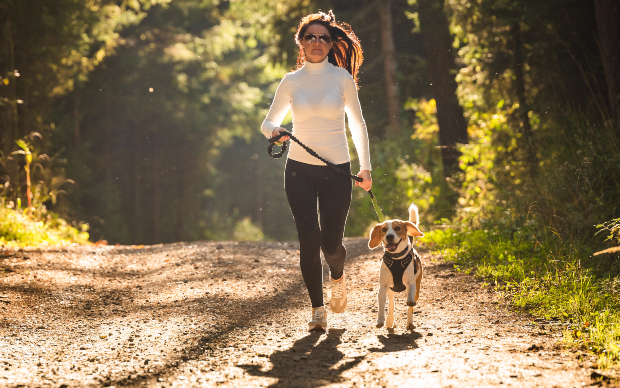 Frau joggt mit Hund an der Leine