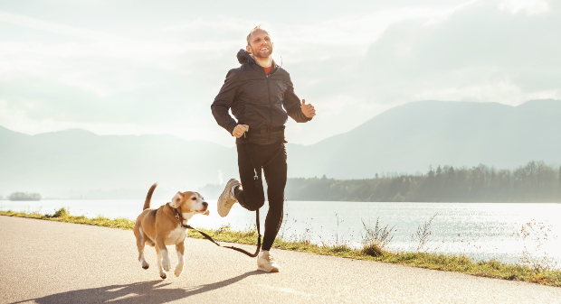 Mann joggt mit seinem Hund am See